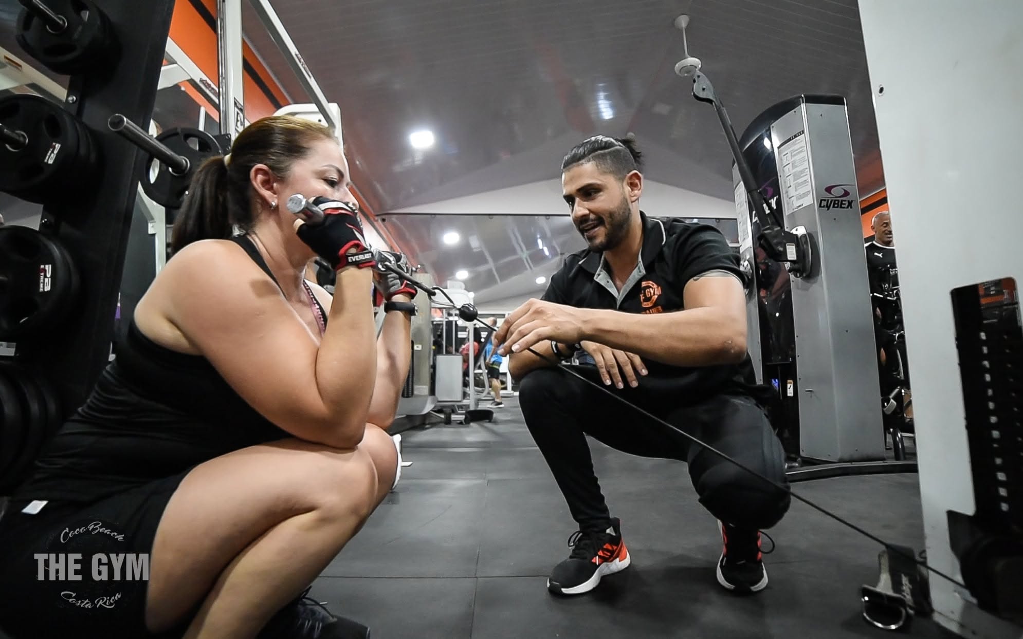 A coach guiding a member through a cable exercise at The Gym